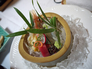Bowl of Luxury Gourmet sashimi set on ice served in bamboo trunk, shrimp and tuna fancy decorated...