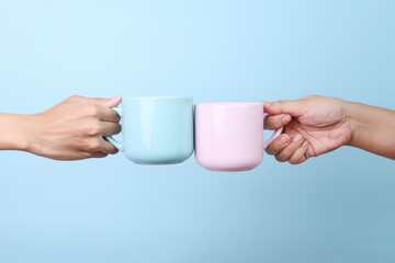 Female hands holding blue and pink cup hot coffee mockup isolated on blue background