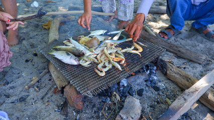 Obraz premium The Activities Of People Grilling Fish And Shrimp On The Beach