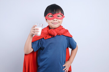 Little superhero boy with glass of milk isolated on white background