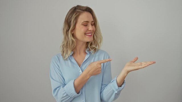Blonde bombshell amazed! young woman in a shirt, confidently presenting, pointing, and smiling on a white isolated background.
