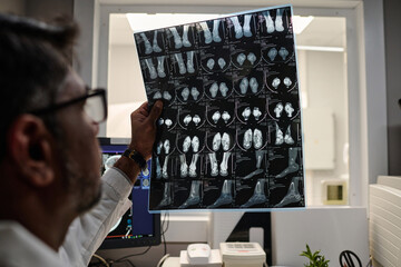 Selective focus closeup of biracial male radiographer working with head CT X-ray scan image