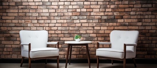 Two white chairs and a table in front of a brick wall