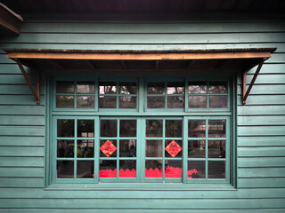 Vintage teal wooden house facade with decorative window and red accents