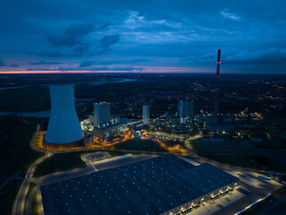 Aerial drone view on a fossil fueled power plant at dusk and night. Cooling tower exterioir....