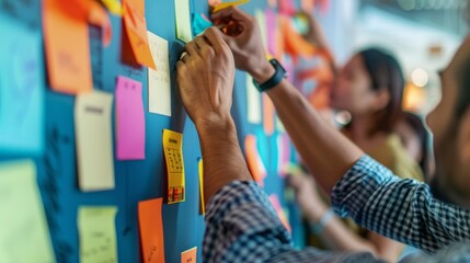 Professionals rearranging sticky notes on a wall during a brainstorming session