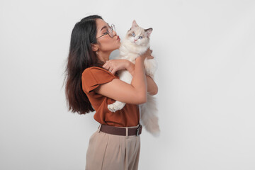Portrait of young Asian woman in brown shirt holding her ragdoll cat and making kiss pouty face...