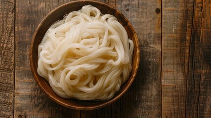 Overhead view of udon noodles in wooden bowl on wooden table, creating an inviting composition