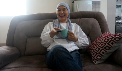 Front view of muslim woman laughing while watching movie at home