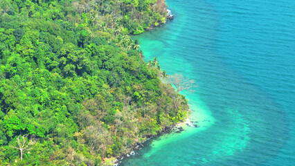 An enchanting tapestry of turquoise waves and lush greenery unfolds beneath the drone's lens,...