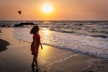 Happy beautiful young Indian woman admiring the sunset at the Goa beach. Delightful girl enjoying...