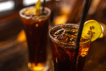 Negroni Cocktail in crystal glass with ice cubes and orange slices with blurred sea beach in background