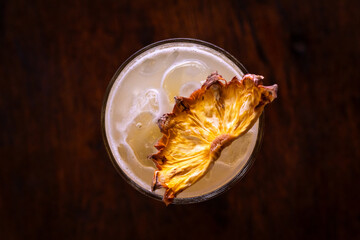 cocktail in a Whiskey glass with dried pineapple garnish
