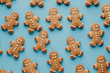 A row of gingerbread men are smiling on a blue background. The cookies are decorated with icing and have white dots on their faces