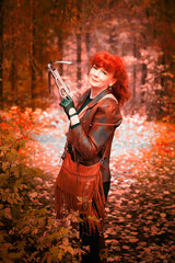 Mature model portraying a royal huntress with red curve hair is hunting with a crossbow in the in...