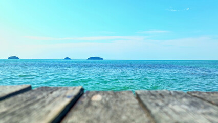 The tranquil turquoise sea, framed by a wooden bridge, leads the eye to a distant island under a vibrant blue sky, crafting a mesmerizing, idyllic setting. Koh chang, Trat Province, Thailand. 
