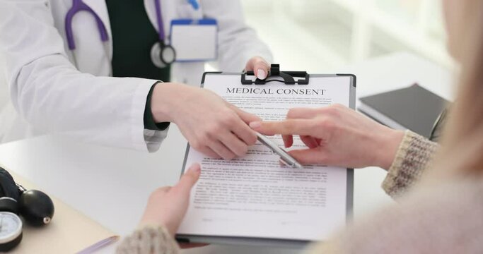 Female patient studying reads signing informed consent in doctor office