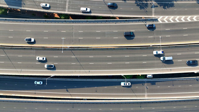 Aerial view, High above, a drone gracefully glides over a bustling highway, capturing the endless flow of vehicles below. Automobiles and Public Transit concept. Bangkok, Thailand.
