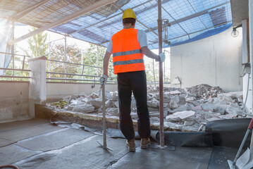 Home repair. Reconstruction of the waterproofing and floor insulation of a terrace - roof. In the photo a worker with pickaxe and reflective jacket, pile of rubble and new laid bituminous sheath