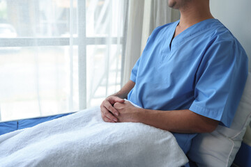 Male patient sitting holding hands smiling Relaxing in bed after receiving medical attention at the...