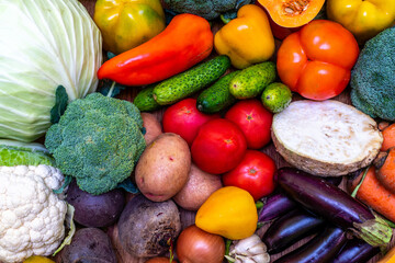 Various vegetables are laid out on a wooden table. Large assortment of vegetables food. pumpkin cabbage broccoli pepper tomatoes carrots and others