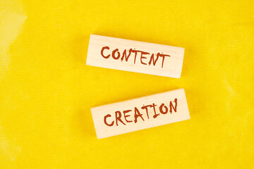 Concept word Content creation on wooden blocks on a yellow background