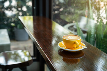 Hot coffee latte with latte art milk foam in cup mug on wood desk on top view. As breakfast In a...