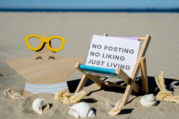 NO POSTING NO LIKING JUST LIVING text on paper greeting card on background of beach chair lounge starfish summer vacation decor. Concept of social media technology detox Sandy beach sun. Holiday