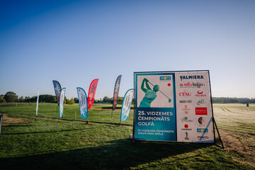Naklejka premium Valmiera, Latvia - August 12, 2023 - Golf event signage and sponsor banners on a clear morning at a golf course.