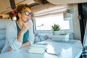 One adult woman reading and writing notes inside a camper van. Modern people lifestyle traveler and...