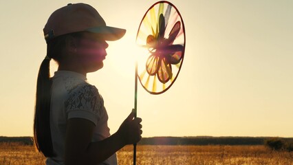 toy windmill sunset, child girl looking sunset holding windmill hand, catching wind glare sunset,...