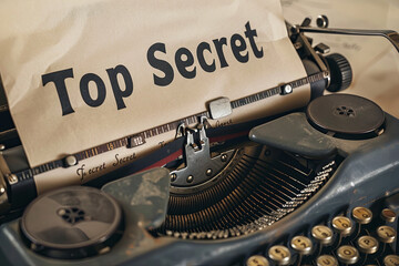 Top Secret phrase closeup being typing and centered on a sheet of paper on old vintage typewriter mechanical, with writing " Top Secret "
