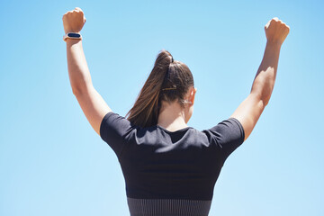 Blue sky, celebrate and back of woman for fitness, exercise and running victory outdoors. Sports, happy and person with hands up for workout, training and challenge in nature for wellness and health