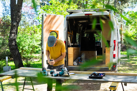Man sanding wood to camperize a camper van
