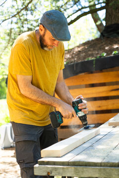 Middle-aged Caucasian man working sanding wood with an electric sander