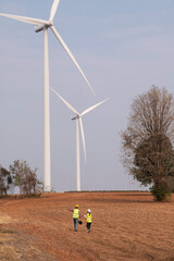 Female and male engineers discuss installing wind turbines, clean energy that reduces carbon...