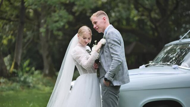 The bride and groom linger by the retro car on their wedding day.