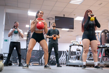 In a dynamic fitness class, participants perform kettlebell squats guided by their instructor...