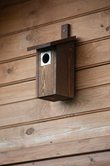 Wooden birdhouse on a wooden wall, close-up.