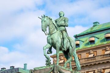 The statue of Gustav II Adolf is captured here standing proudly in Stockholm, Sweden, with clear skies and surrounded by the city architecture.