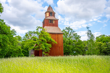 Seglora Church rustic red wooden facade stands out against the lush greenery on a bright summer day...