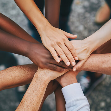 Close-up of diverse hands stacked together, portraying unity and teamwork