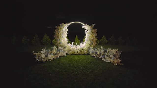 Wedding arch decorated with flowers at night.