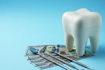 Dollar money bills and tooth model on a bluebackgound with copy space