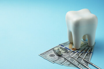 Dollar money bills and tooth model on a bluebackgound with copy space