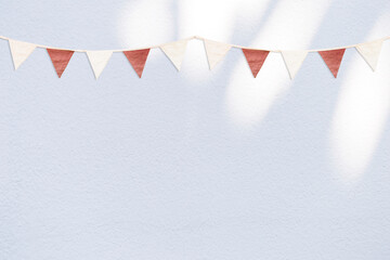 Vintage style bunting flag on white cement wall background, simple fabric party flag on white...