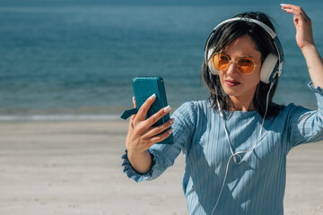 woman with headphones and mobile phone enjoying on the beach