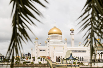 Gold Dome of Omar Ali Saifuddien Mosque through palm trees in Brunei Darussalam on Borneo in Southeast Asia - obrazy, fototapety, plakaty