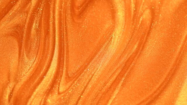Beautiful abstract golden liquid paint background, beauty gold backdrop texture. Metallic gold paint, art design. Yellow shimmering surface close-up. Golden bright glitter texture, macro shot