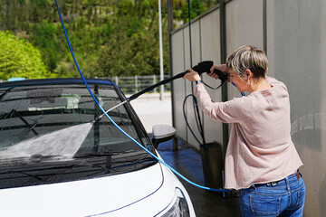 A diligent woman engaging in thorough car wash at a self-service bay.